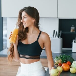 With fresh orange juice. Young european woman is indoors at kitchen indoors with healthy food.